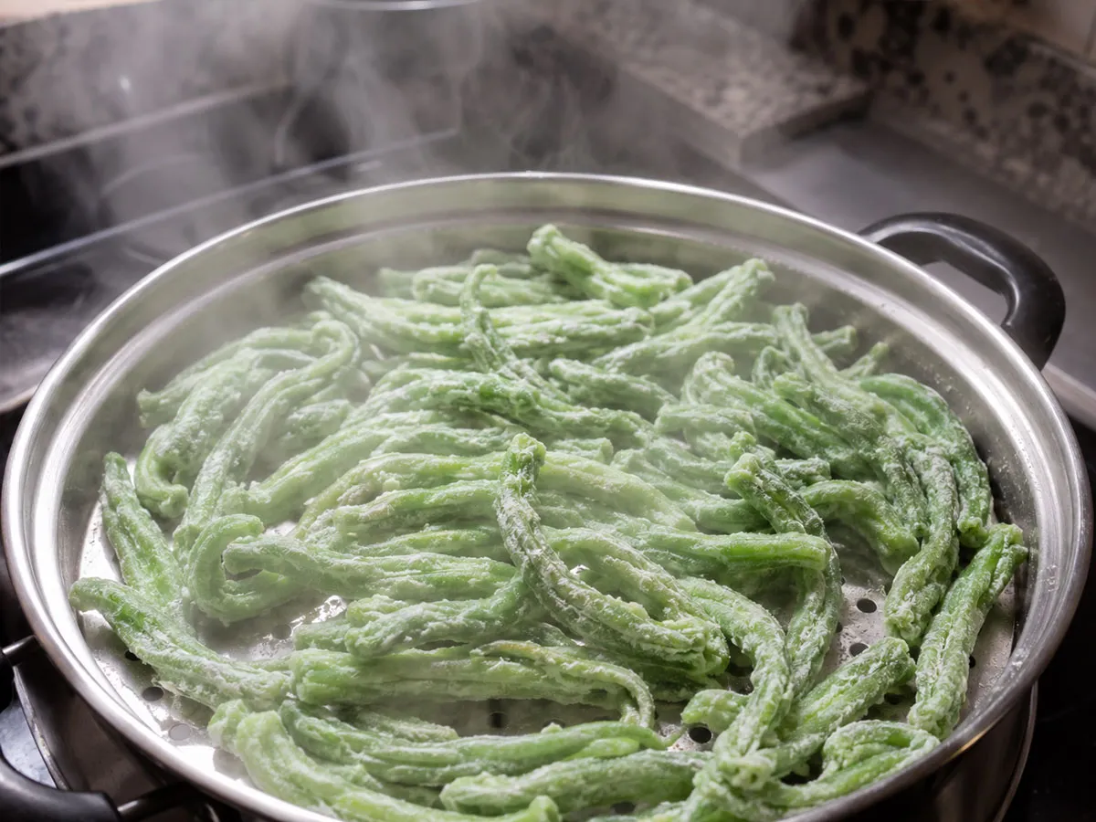 가루를 입힌 꽈리고추를 찜기에 펼쳐 짧게 쪄 쫀득한 식감을 만드는 모습.