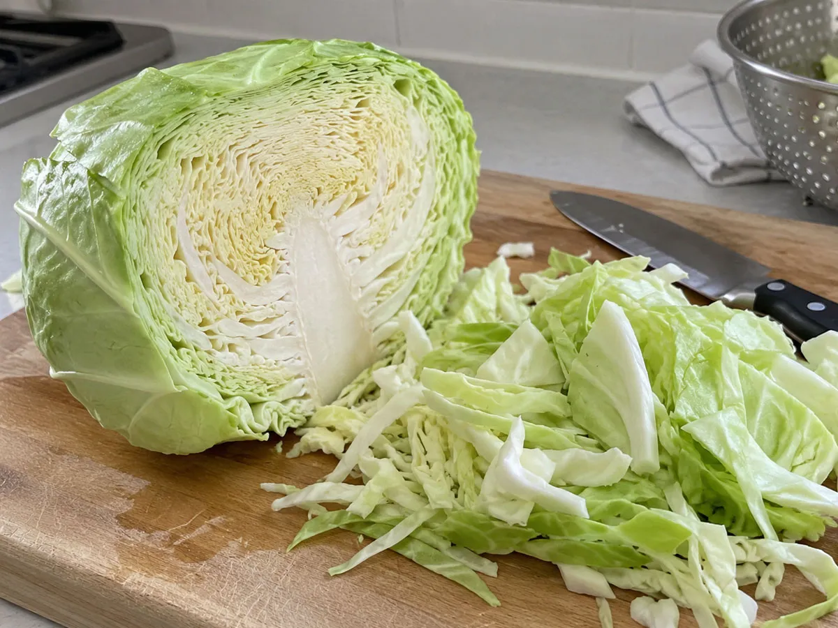도마 위에 반으로 자른 양배추와 먹기 좋게 손질한 양배추가 놓여 있다. 가격 부담이 적고 쉽게 구할 수 있어 꾸준히 식단에 활용하기 좋은 채소라는 점을 보여준다.