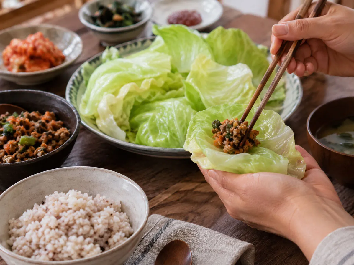 부드럽게 익은 양배추 잎에 밥과 속재료를 곁들여 쌈으로 즐기는 모습이다. 양배추의 촉촉한 식감과 자연스러운 단맛을 살린 건강 식단의 완성 장면이다.
